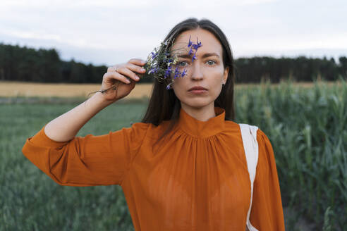 Frau hält blaue Blume im Feld - TOF00188