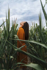 Frau mit zurückgeworfenem Kopf inmitten von Maiskulturen im Feld - TOF00191