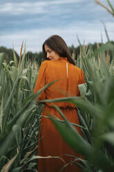 Smiling woman standing amidst corn crops in field - TOF00196