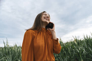 Frau spricht in einem Maisfeld mit einem Mobiltelefon - TOF00205