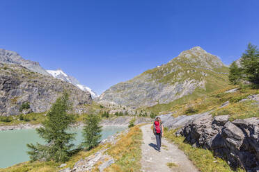 Ältere Frau beim Spaziergang in der Nähe des Margaritzestausees unter blauem Himmel im Nationalpark Hohe Tauern, Salzburg, Österreich - FOF13736