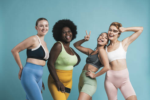 Cheerful multiracial women standing against blue background - OIPF03762