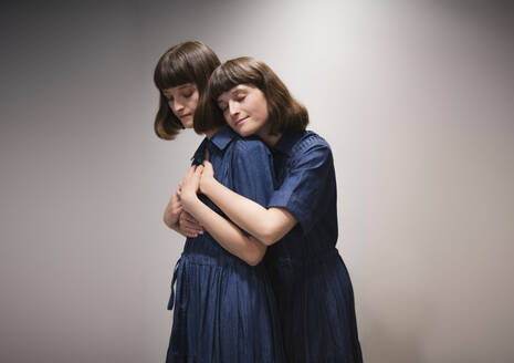 Lächelnde Zwillingsschwestern, die sich gegenseitig unterstützen und trösten - AMWF01968