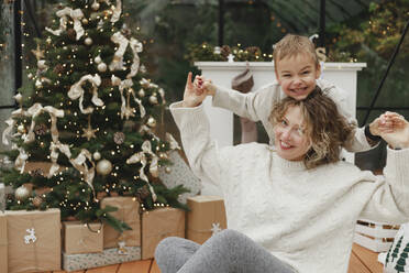 Glückliche Mutter und Sohn haben Spaß in der Nähe von Weihnachtsbaum zu Hause - EHAF00165