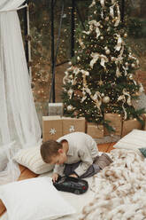 Boy playing with toy car near Christmas tree at home - EHAF00184