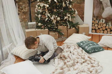 Boy playing with toy car on carpet near Christmas tree at home - EHAF00185