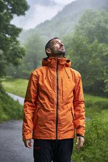 Mann mit orangefarbener Jacke vor einem Berg in den Pyrenäen stehend - VEGF06227