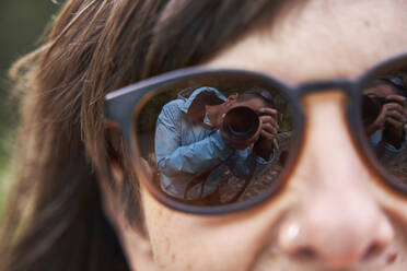 Reflection of man photographing through camera on woman's sunglasses - VEGF06250
