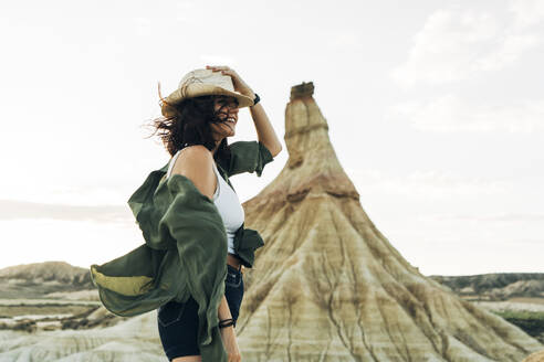 Smiling tourist wearing hat under winds near Castildetierra - DAMF01232