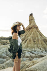 Smiling tourist wearing hat standing near Castildetierra - DAMF01233