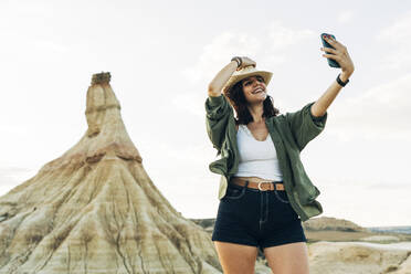 Smiling woman taking selfie with Castildetierra in background - DAMF01235
