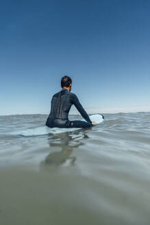 Surfer mit Surfbrett über dem Meer unter klarem blauen Himmel an einem sonnigen Tag - DAMF01264