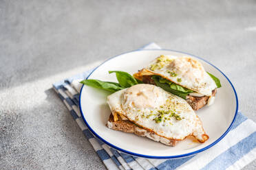 Hohe Winkel der Platte von appetitlichen Toast mit frischem Spinat Blätter gebratene Eier Pesto-Sauce auf blaue Serviette serviert - ADSF51800