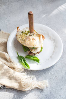 Hohe Winkel der Platte von gesunden Toast mit Spiegelei Pesto-Sauce grüne Kräuter auf grauen Tisch während des Frühstücks - ADSF51804