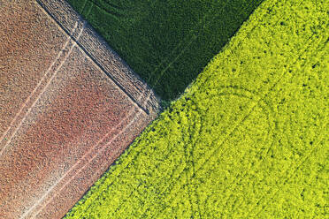 Strukturierte Luftaufnahme von Ackerland mit geometrischen Mustern von gepflügten Feldern in Grün-, Gelb- und Brauntönen - ADSF51901