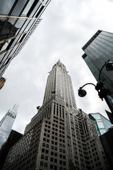 Niedriger Winkel von hohen mehrstöckigen Gebäuden und Chrysler-Gebäude im zentralen Bezirk von New York City gegen bewölkten düsteren Himmel - ADSF52015