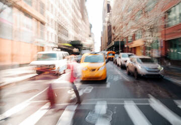 Seitenansicht von unerkennbaren Menschen, die die Straße in der Nähe von modernen Wolkenkratzern im Stadtteil Manhattan in New York an einem sonnigen Tag überqueren - ADSF52030