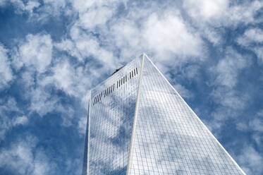 Ein hoher moderner Wolkenkratzer, der in den blauen Himmel ragt, kontrastiert mit einem benachbarten Gebäude in Manhattan, New York, und fängt das Wesen der städtischen Architektur ein. - ADSF52045