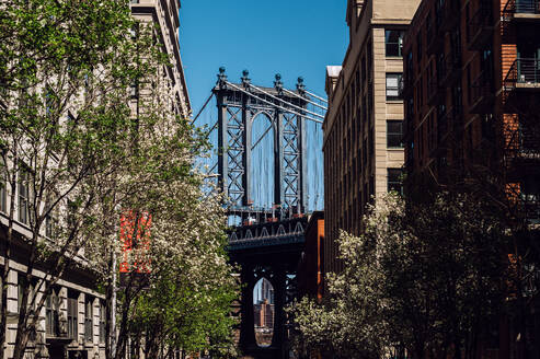 Eine lebhafte Straßenszene in DUMBO, Brooklyn, mit der ikonischen Manhattan Bridge zwischen zwei historischen Backsteingebäuden. - ADSF52050