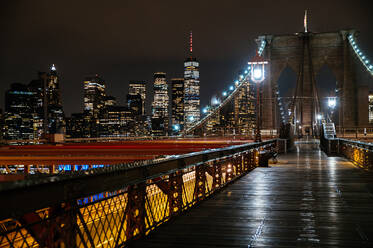Night view of the Brooklyn Bridge walkway leading to the sparkling Manhattan skyline. - ADSF52055