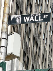 Niedriger Winkel des Hinweisschildes mit der Aufschrift Wall Street, das an einem mehrstöckigen Gebäude in New York City hängt - ADSF52069