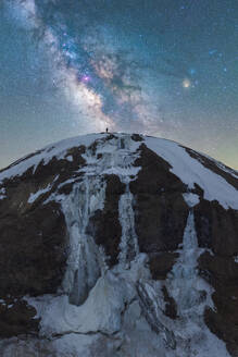 Ein atemberaubender Blick auf die Milchstraße über dem Vatnajokull-Nationalpark in Island, mit einer Person, die sich von den Sternen abhebt und die Weite der Natur unterstreicht. - ADSF52183