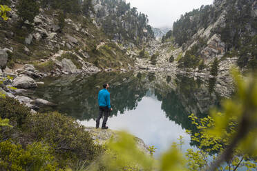 Rückenansicht eines männlichen Wanderers in Freizeitkleidung in der Nähe des Sees Sant Maurici in den Bergen des katalanischen Nationalparks - ADSF52214