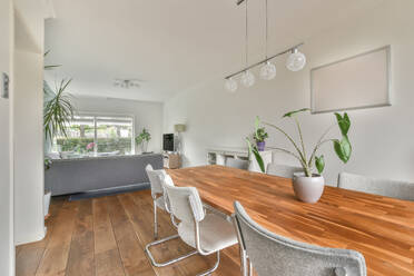 Holztisch und Stühle im Esszimmer eines modernen Hauses mit Sofa und Fernseher im Hintergrund - ADSF52247