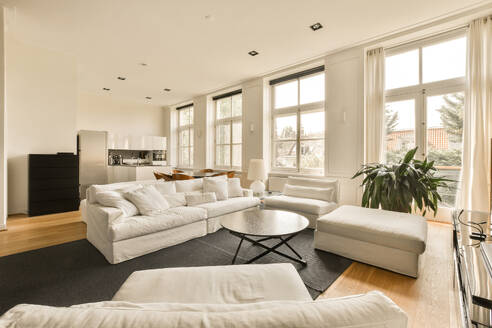 Weißes großes bequemes Sofa am Couchtisch im geräumigen Wohnzimmer eines luxuriösen Hauses mit Küche im Hintergrund - ADSF52254