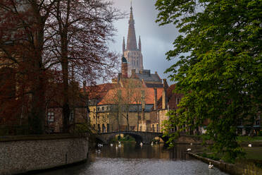 Historic architecture of Brugge with the Church of Our Lady spire overlooking a canal bridge, Belgium - ADSF52373