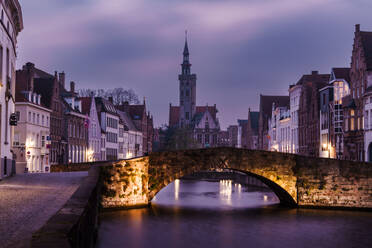 Die Dämmerung legt sich über die ruhigen Grachten und mittelalterlichen Gebäude von Brügge, Belgien, mit einer Steinbrücke im Vordergrund - ADSF52374