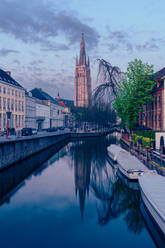 Dawn light casts a soft glow on the Church of Our Lady and the calm canal in Brugge, Belgium - ADSF52375