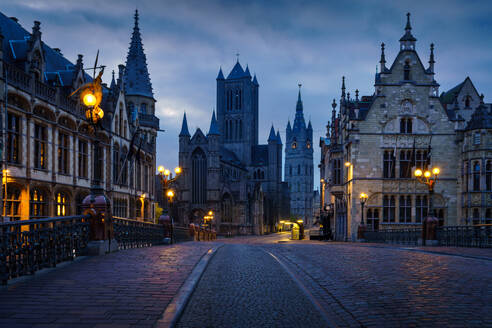 Historische Gebäude und Straßenbeleuchtung in der Morgendämmerung in Gent mit der St.-Bavo-Kathedrale im Hintergrund - ADSF52378