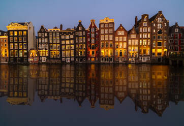 The golden hour reflects on Amsterdam's iconic canal houses, mirrored perfectly in the still water - ADSF52380