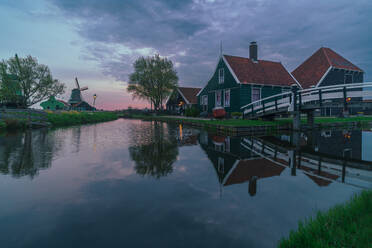 Eine ruhige Abendszene mit typisch holländischen Häusern und einer Windmühle, die sich in den ruhigen Gewässern der Zaanse Schans spiegelt - ADSF52381