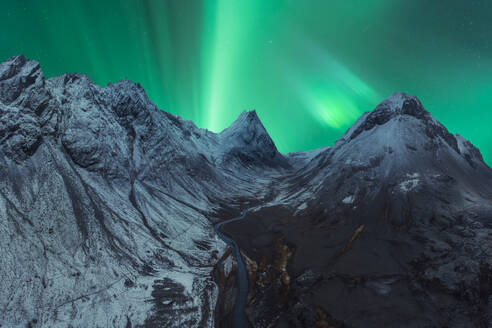 Scharfe Berggipfel unter einem pulsierenden Nordlicht in Island mit einem schmalen Fluss in der Mitte - ADSF52535