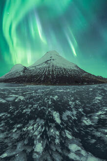 Atemberaubender Blick auf das Nordlicht, das über den sternenübersäten Nachthimmel tanzt, über einer ruhigen, schneebedeckten Berglandschaft im Vatnajokull-Nationalpark, Island - ADSF52536