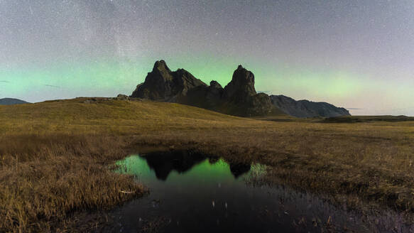 Ein atemberaubender Blick auf den Sternenhimmel und die isländischen Nordlichter, die sich in einem ruhigen Bergsee in Eystrahorn spiegeln - ADSF52540