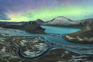 Das Polarlicht erhellt den Nachthimmel über einem ruhigen Vulkankratersee in Island, flankiert von schneebedeckten Bergen und verschlungenen Flussdeltas - ADSF52541