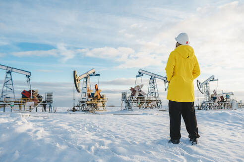 Junger Ingenieur auf einem Ölförderfeld im Winter - OLRF00103