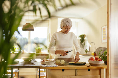 Lächelnde Frau bei der Zubereitung von Apfelkuchen in der Küche zu Hause - EBSF04326