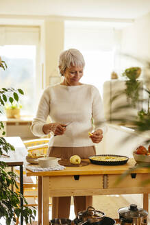 Happy woman cutting apples for pie in kitchen - EBSF04329