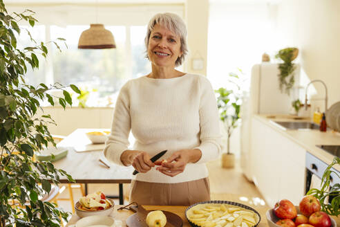 Happy woman preparing apple pie in kitchen at home - EBSF04330