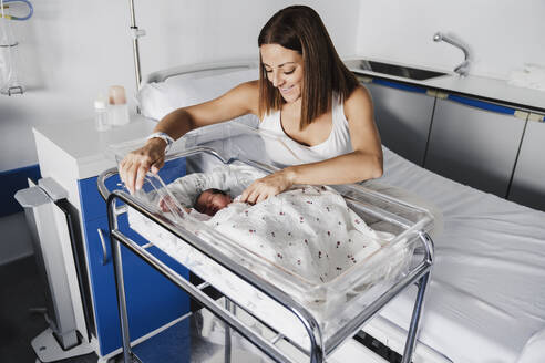 Happy mother with baby daughter in hospital bed - EBBF08271
