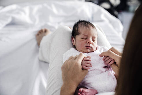 Baby girl sleeping on mother's lap in hospital - EBBF08278