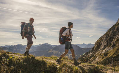 Young backpackers hiking on mountain trail in Tannheimer Tal, Tyrol, Austria - UUF30987