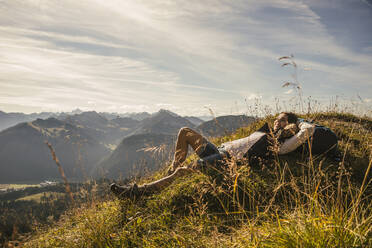 Junge Frau, die sich auf einem Felsen im Tannheimer Tal ausruht, Tirol, Österreich - UUF30990