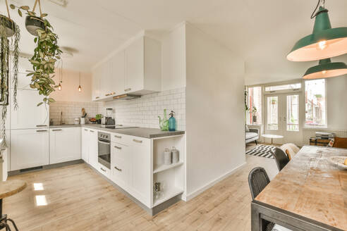 Induction and sink on countertop of modern kitchen of luxurious apartment with dining table and chairs - ADSF52559