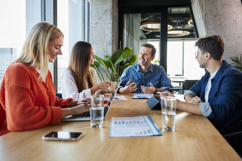 Lächelnde Geschäftskollegen bei einem Treffen im Konferenzraum im Büro - BSZF02388