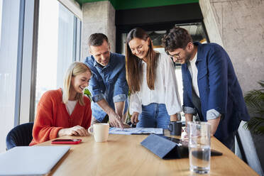 Lächelnde Geschäftsleute, die im Büro über Daten diskutieren - BSZF02393